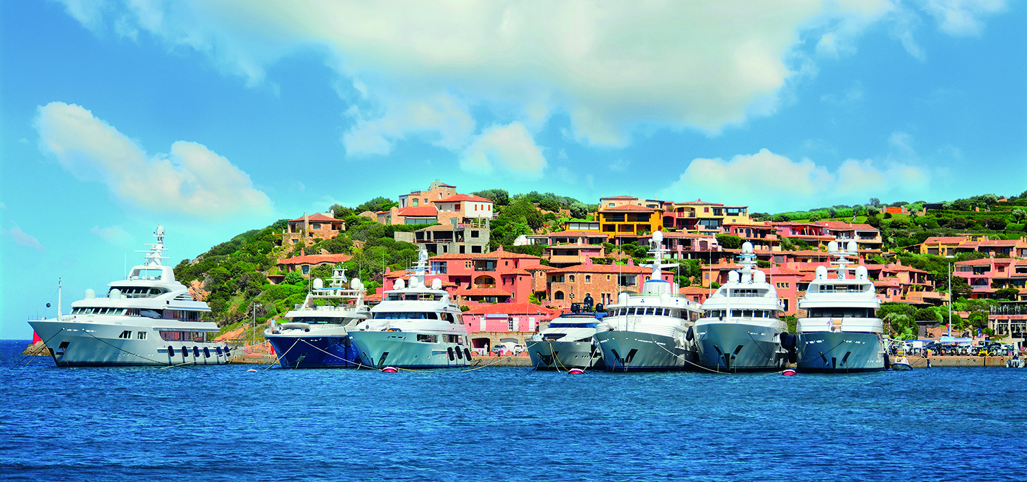 Sardinia yacht charter with luxury superyacht in front of a town