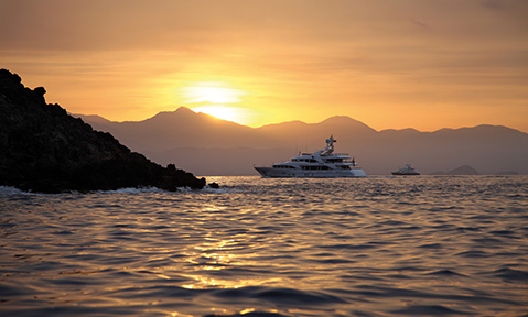 A luxury yacht for charter in Turkey heads towards a bay at sunset
